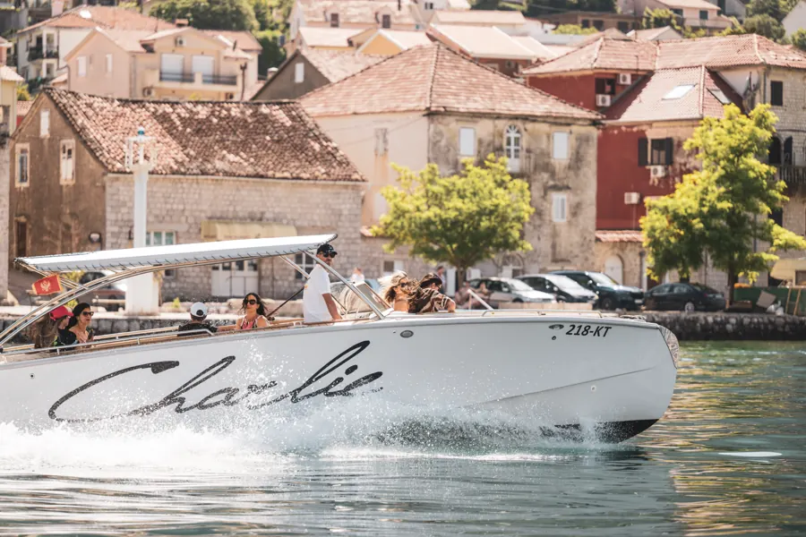 The speedboat Charlie passing the waterfront of Perast